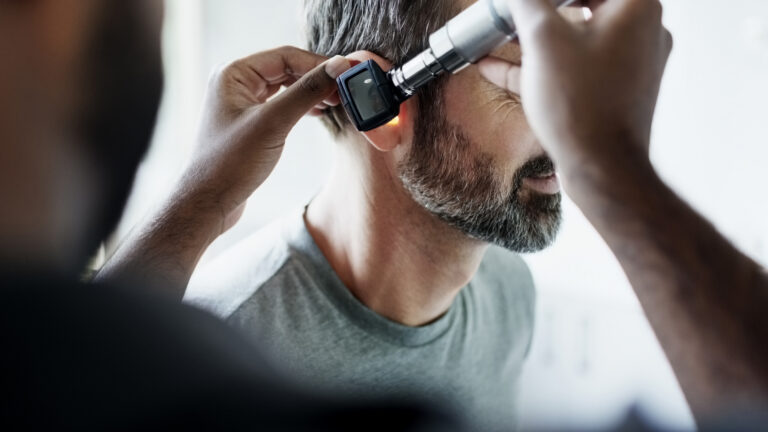 A patient receives a hearing exam with an otoscope